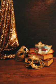 blue-golden-masks-with-vintage-books-glitter-sequins-textile-wooden-desk.jpeg