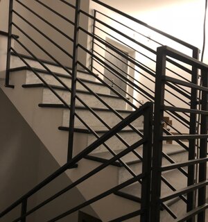 Scala in ferro con parapetto geometrico a linee orizzontali per edificio residenziale
