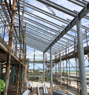 Struttura portante in acciaio zincato per copertura terrazzo in fase di montaggio, con ponteggi e vista mare sullo sfondo