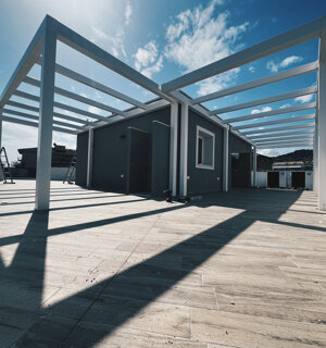 Copertura in acciaio con travi parallele e ombre proiettate su pavimento in cantiere