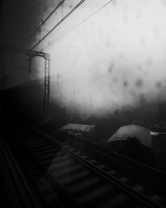 Binari, linee elettriche e strutture di servizio nella nebbia mattutina, visti da un treno. - Tracks, overhead lines and railway service buildings in the morning mist, seen from a train.