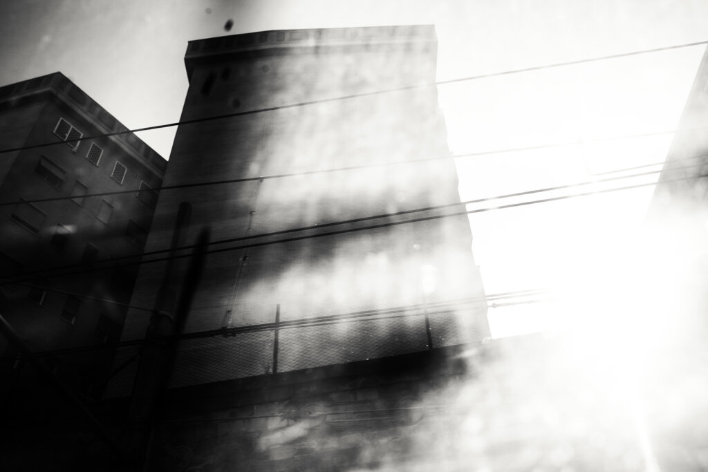 Fotografia in bianco e nero di Antonio Crialesi di un palazzo in zona Ostiense a Roma visto da un vagone del treno Roma-Lido (Metromare) - Black and white photograph by Antonio Crialesi of a building in the Ostiense area of Rome, seen from a Rome-Lido (Metromare) train car