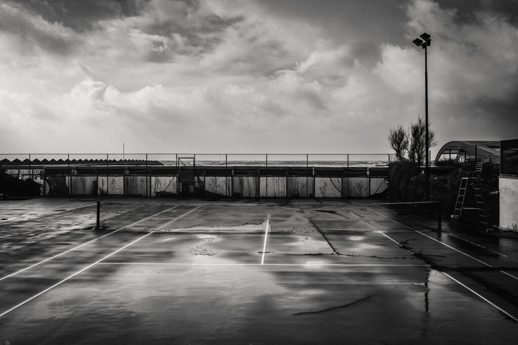 Campo da tennis bagnato dalla pioggia in uno stabilimento balneare abbandonato a Ostia. - Rain-soaked tennis court at an abandoned beach club in Ostia.