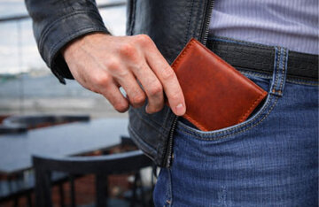 Portafoglio in pelle artigianale mentre viene messo in tasca da un ragazzo
