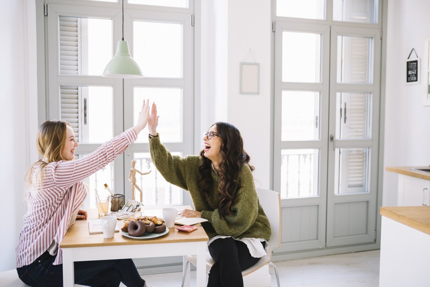 laughing-women-high-fiving-table.jpeg