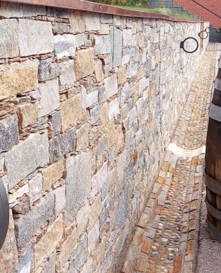 Rivestimento di un vecchio muro in cemento con pietra naturale e inserimento lampade in un'azienda vinicola in provincia di Vercelli