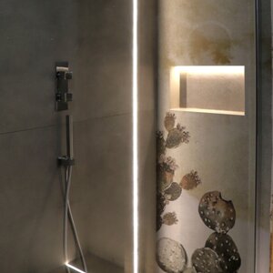 Vano doccia con rivestimento in carta da parati e nicchia portaoggetti illuminata