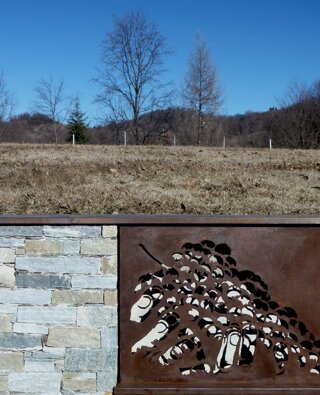 Rivestimento di un vecchio muro in cemento con pietra naturale e lastra in ferro finitura Corten con intagli artistici in azienda vinicola in provincia di Vercelli