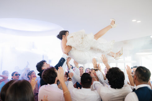 Momento clou di un matrimonio con la sposa sollevata dagli invitati durante il party Vida Loca Events.