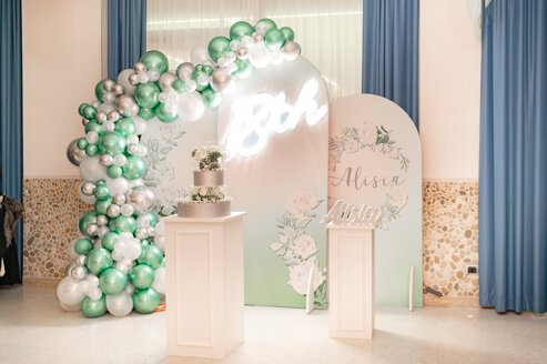 Allestimento elegante per festa di 18 anni con palloncini, insegna neon e torta scenografica Vida Loca Events.