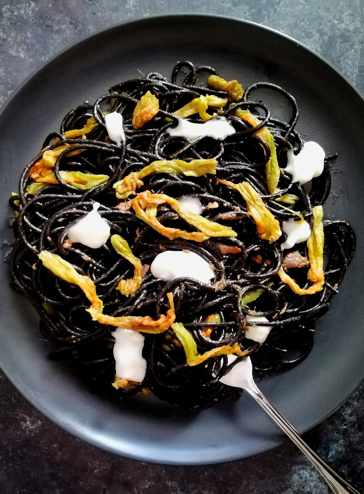 Spaghetti al nero di seppia cacio e pepe con fiori di zucca e alicizucca e alici