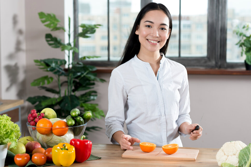 portrait-of-young-woman-standing-near-kitchen-counter-with-different-types-of-vegetables-and-fruits.jpeg