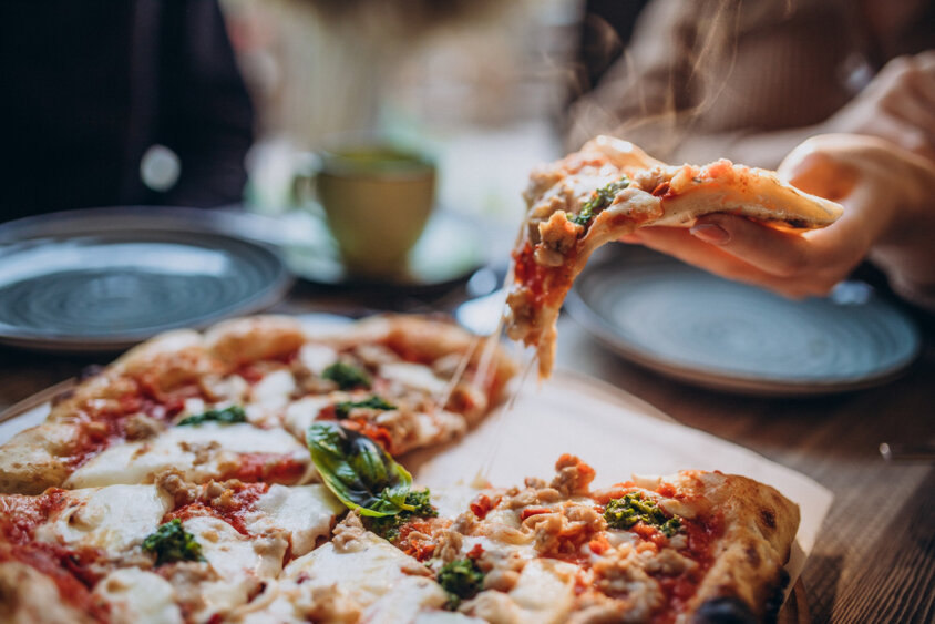 three-firends-together-eating-pizza-in-a-cafe.jpeg