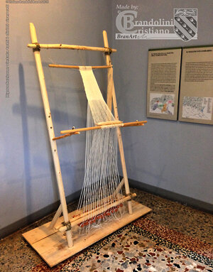 Riproduzione di un telaio da tessitura verticale con pesi in argilla reniformi. Età Neolitica.