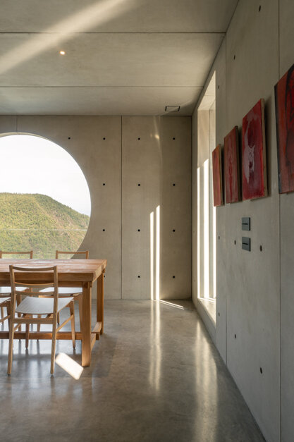Finestra circolare di cemento con vista sui meandri del Trebbia, omaggio a Carlo Scarpa