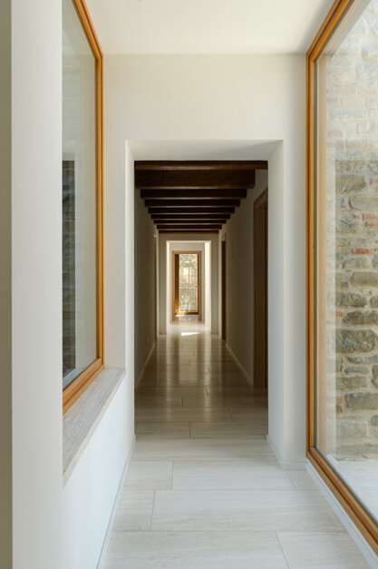 Dettaglio pavimento in travertino posato a correre con infissi in rovere, linguaggio materico unitario Effevu House