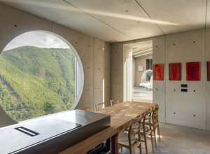 Finestra circolare scavata nel cemento con vista sui meandri del Trebbia, omaggio a Carlo Scarpa