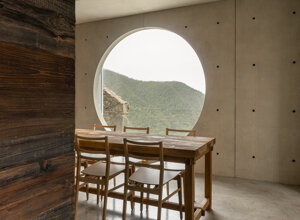 Finestra circolare scavata nel cemento con vista sui meandri del Trebbia, omaggio a Carlo Scarpa