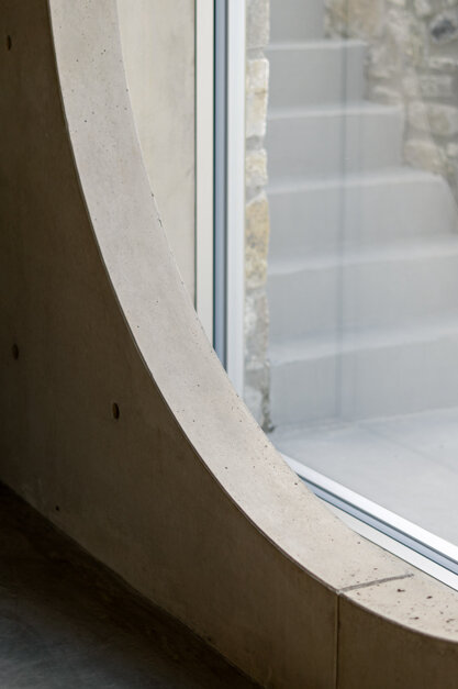 Finestra circolare di cemento con vista sui meandri del Trebbia, omaggio a Carlo Scarpa