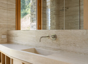 Effevu House, bagno con lavabo e rivestimenti in travertino