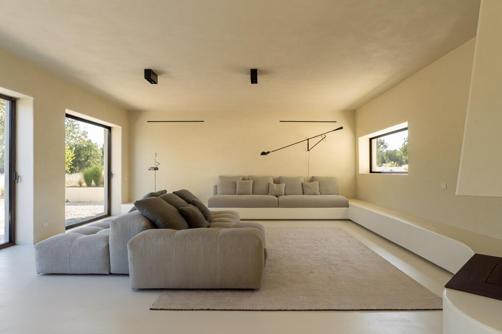 Soggiorno minimalista di Casa E con ampie vetrate affacciate sulla campagna pugliese