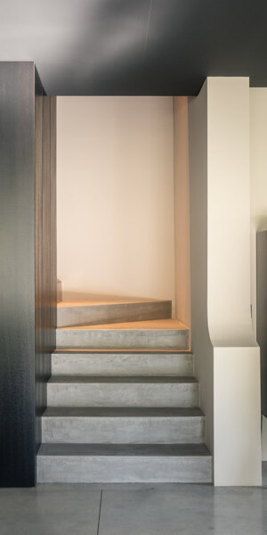 Zona giorno di Casa AF con camino centrale e vetrate a tutta altezza sul giardino