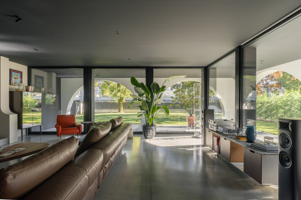 Zona giorno di Casa AF con camino centrale e vetrate a tutta altezza sul giardino