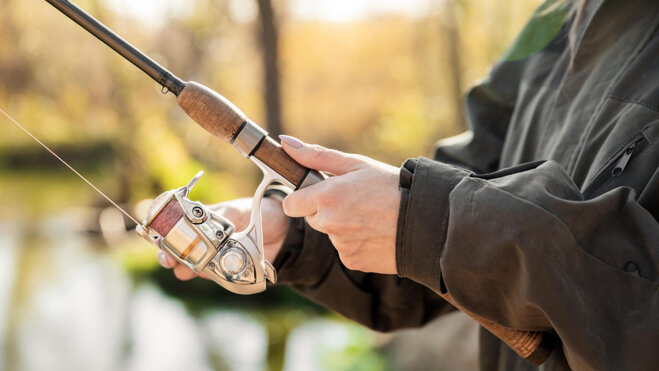 close-up-woman-holding-fishing-rod-with-reel-sport-fishing.jpeg