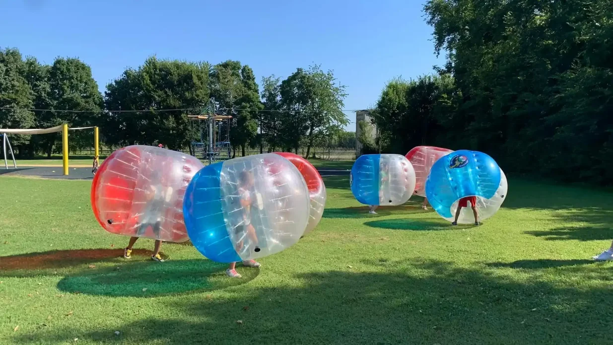 ragazzi che giocano a bubble soccer con l'attrezzatura di Bubble Soccer italia in un campo al coperto sintetico
