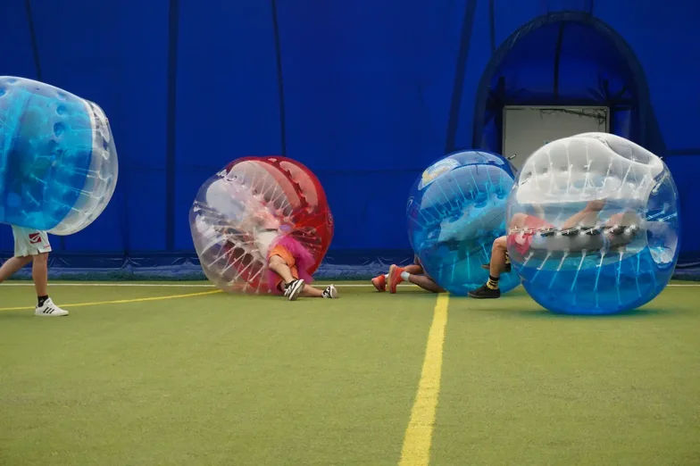 Giocatori di bubble soccer a terra in un campo sintetico da calcio a 5 a Padova