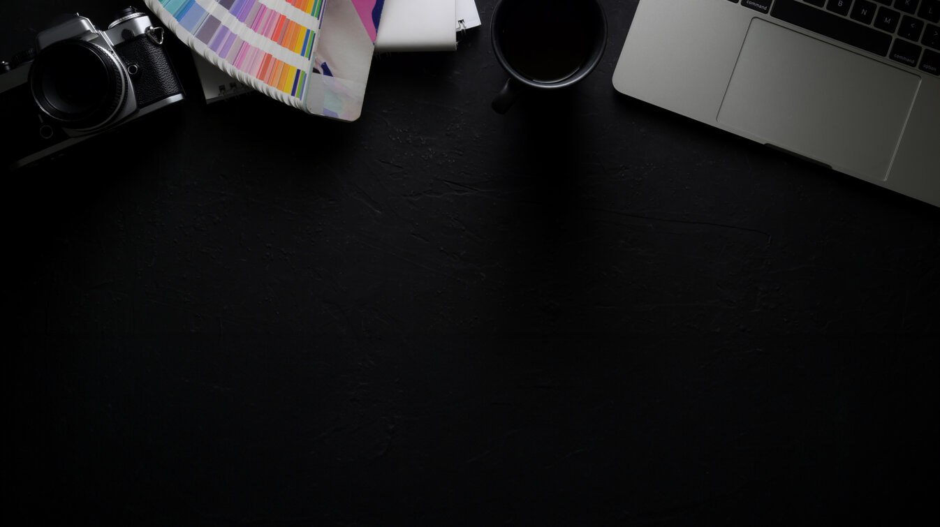 dark-modern-designer-workspace-with-laptop-camera-designer-supplies-coffee-cup.jpeg