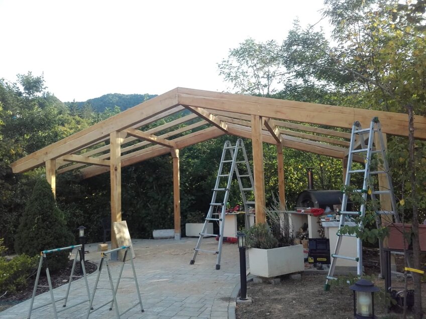 Costruzione di una tettoia in legno con travi portanti e copertura inclinata, realizzata artigianalmente da Bespokewoodart Costruzione di una tettoia in legno con travi portanti e copertura inclinata, realizzata artigianalmente da Bespokewoodart