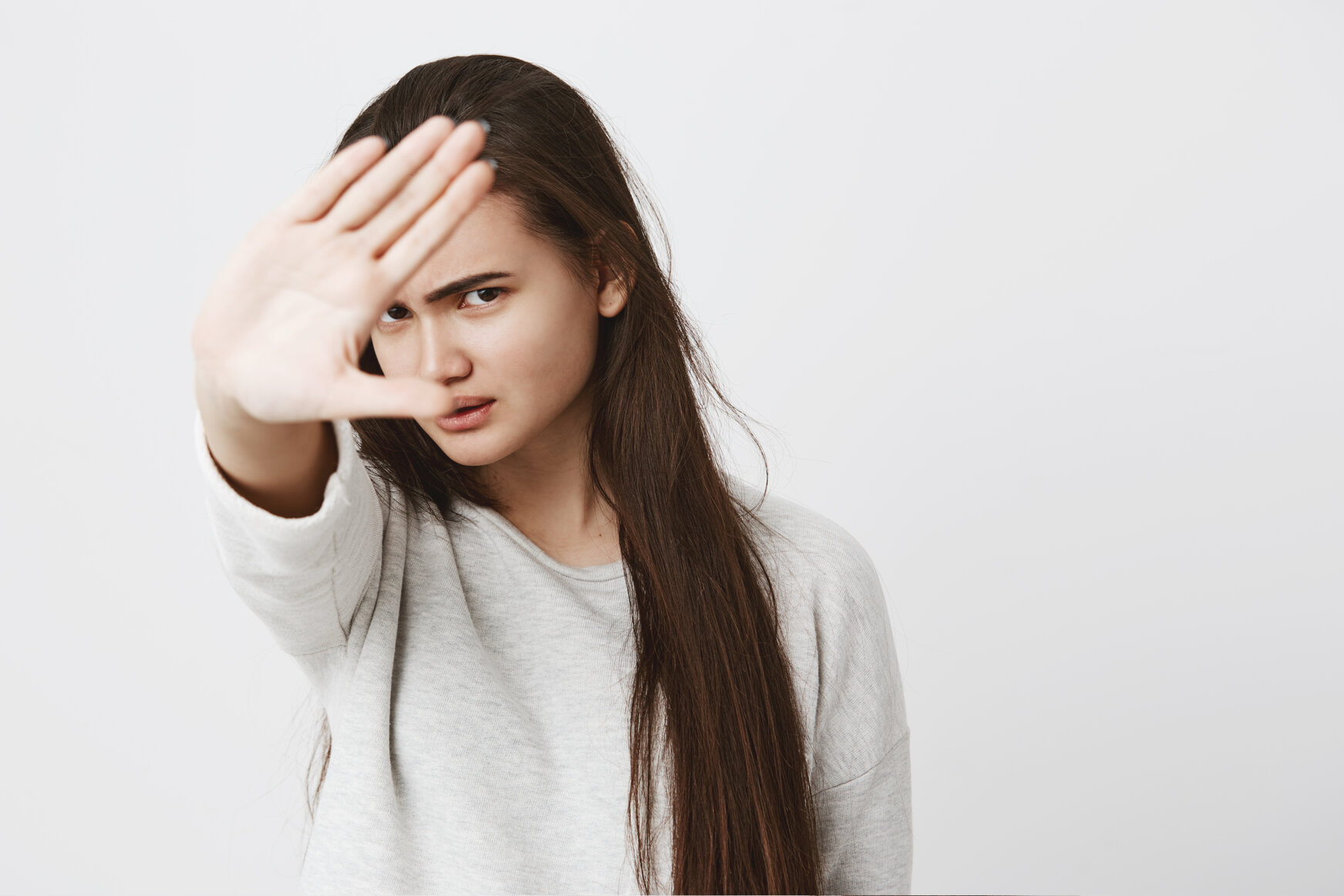 close-up-view-teenage-woman-with-dark-long-hair-making-stop-gesture-with-hand-frowning-face.jpeg