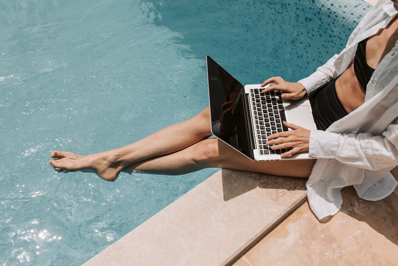 Lavorare in vacanza fa male al business: l'errore che sembra dedizione una donna al PC ai bordi di una piscina