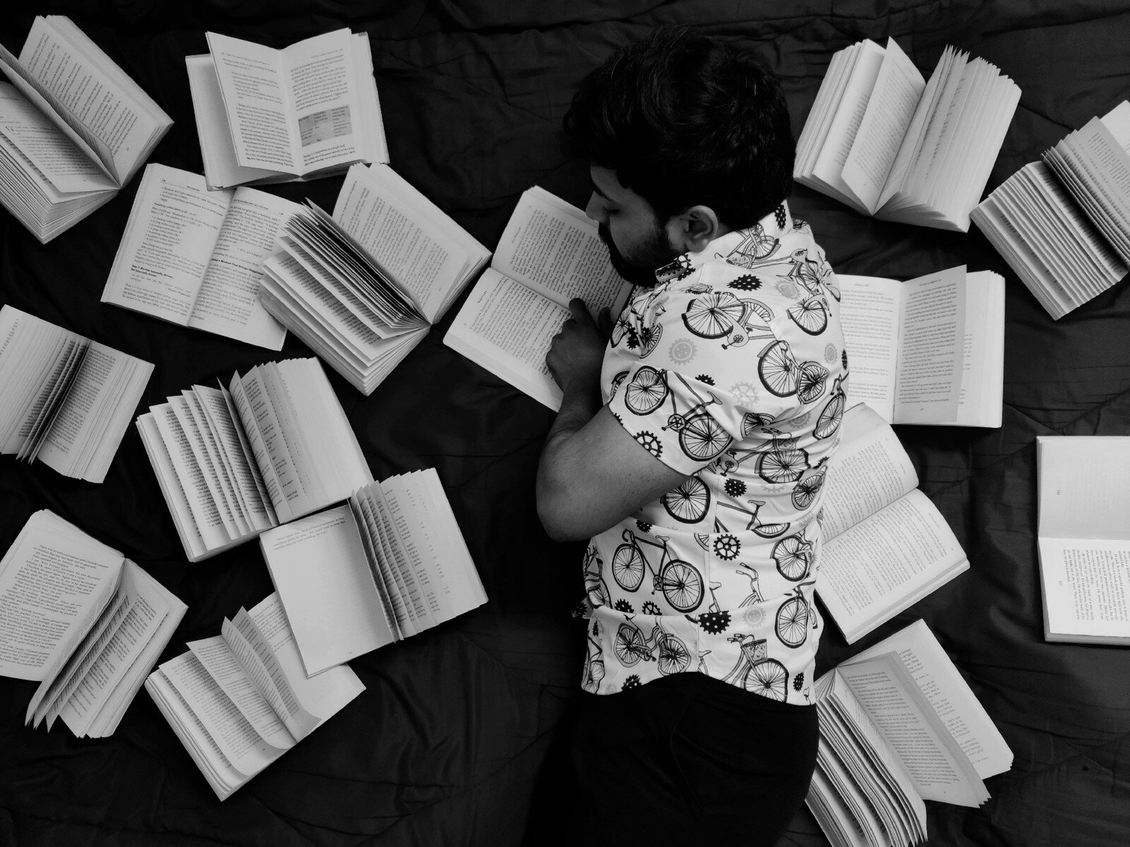 un ragazzo legge sdraiato fra molti libri