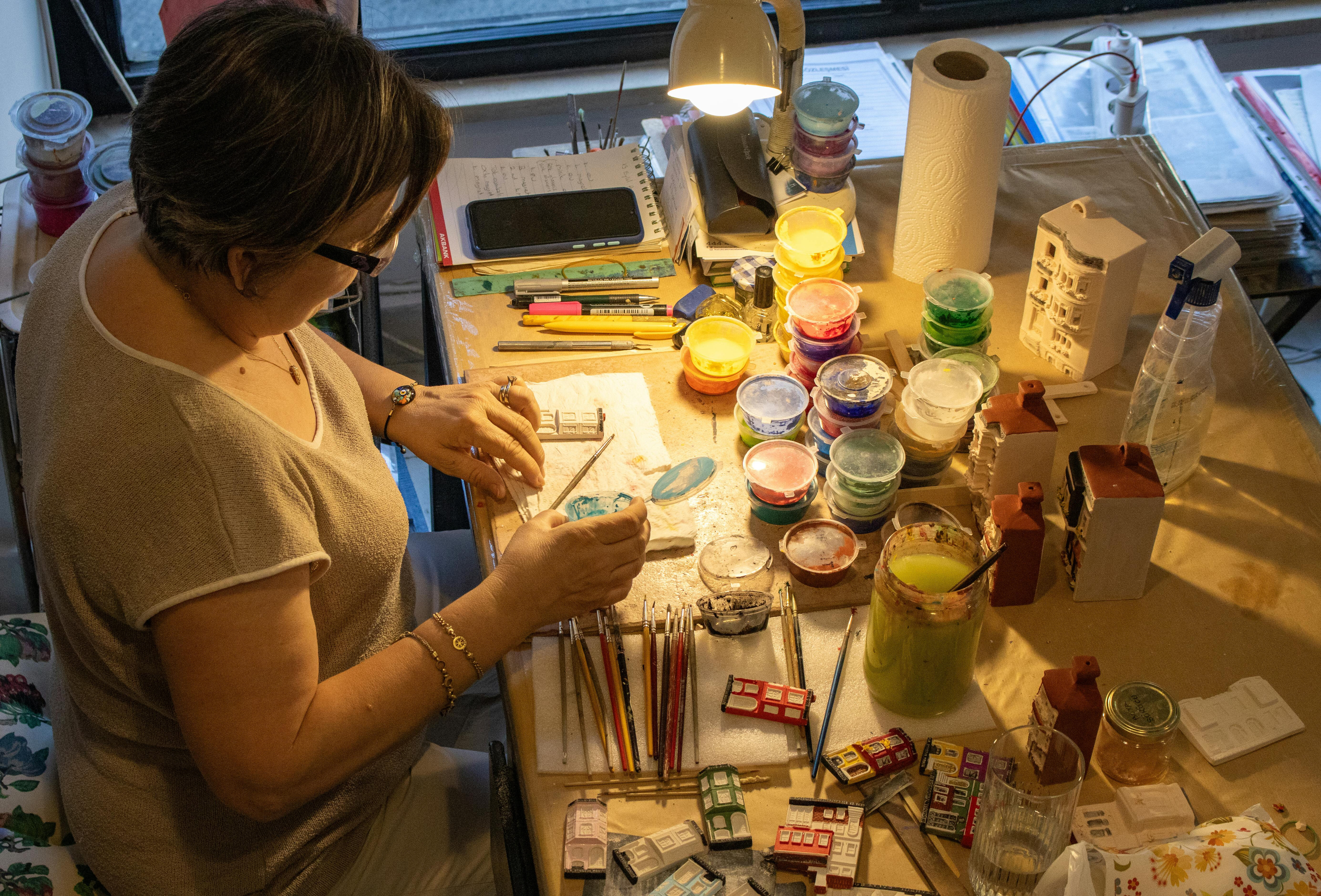una donna circondata da barattoli di colori nel suo piccolo laboratorio domestico