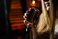 Cantante donna con microfono, luci soffuse, nell'attesa di cantare 