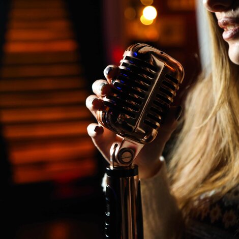 Cantante donna con microfono, luci soffuse, nell'attesa di cantare 