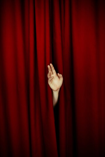 sipario rosso da dove spunta una mano 
