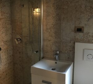 Piccolo bagno composto da doccia a livello del pavimento, lavamani e WC con tavoletta bidet