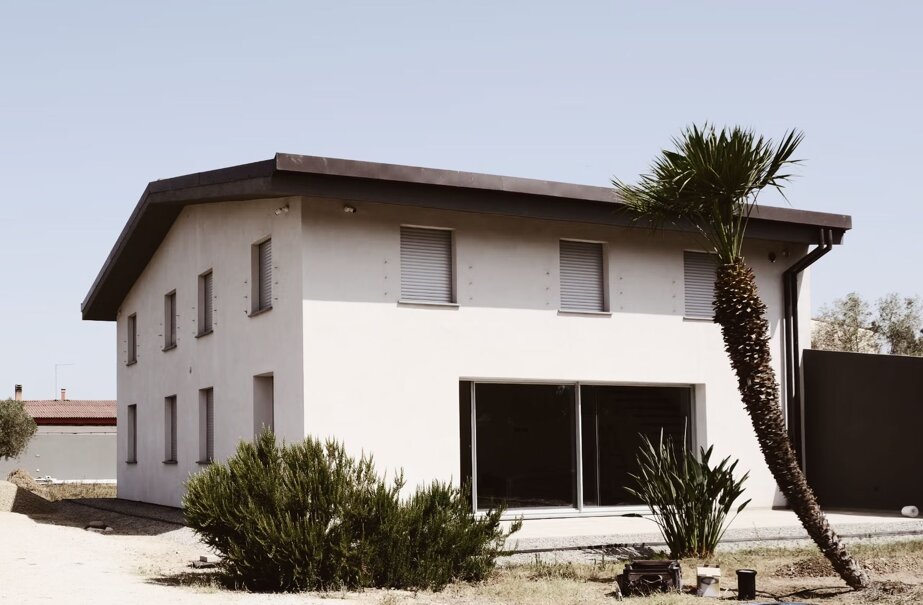 villa bianca ristrutturata con tetto nero e palma