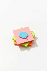 Tre blocchetti di post-it colorati e in cima un blocchetto azzurro a forma di call out dei fumetti, come un pensiero Tre blocchetti di post-it colorati e in cima un blocchetto azzurro a forma di call out dei fumetti, come un pensiero