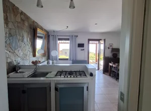 Cucina dell'appartamento con Veranda vista mare e giardino a Stintino