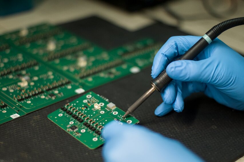 Operatore salda componenti con strumento professionale su scheda elettrica Operatore salda componenti con strumento professionale su scheda elettrica