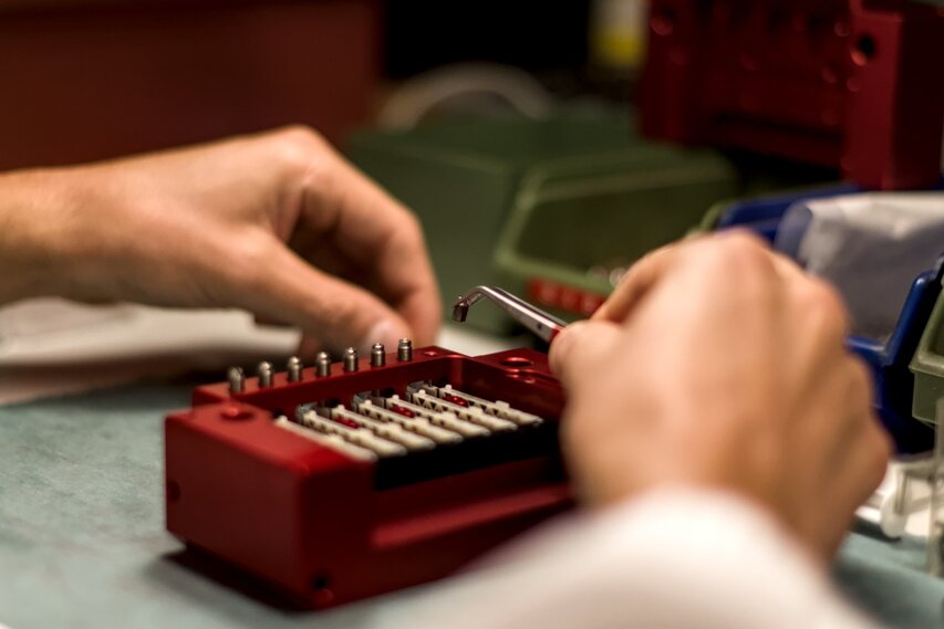 Operatore adopera pinzette per posizionare minuteria meccanica Operatore adopera pinzette per posizionare minuteria meccanica