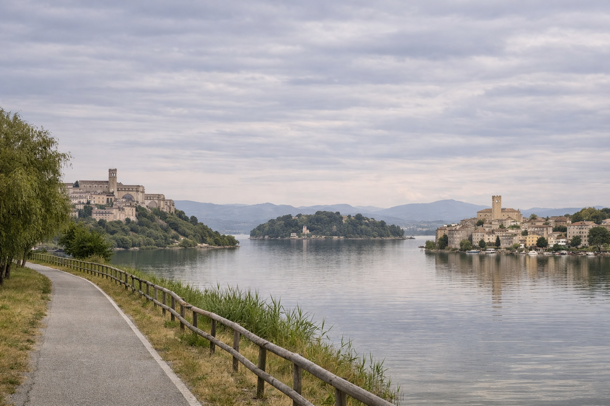 Vista Fusion del Lago Trasimeno con sentiero sul lungolago, borghi storici con campanile e isola centrale