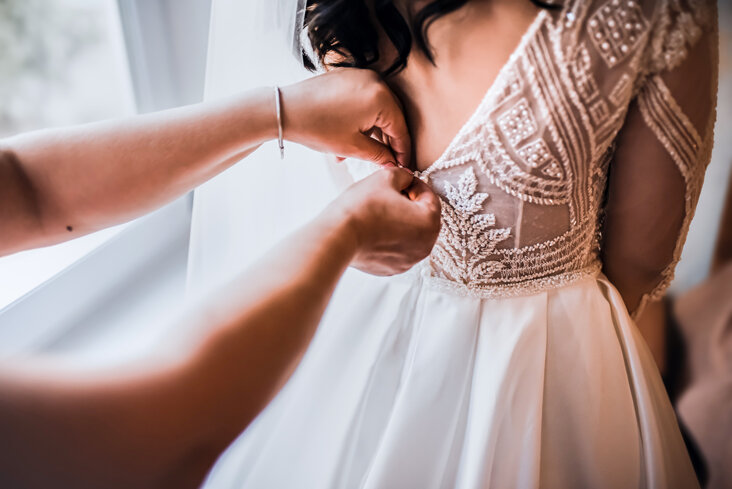 mani che allacciano il vestito da sposa