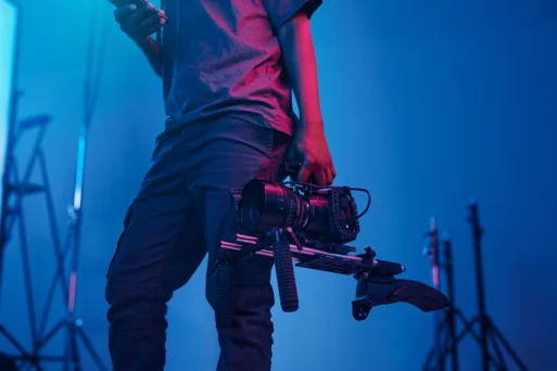 operatore video che tiene in mano una videocamera su rig professionale in studio con luce blu