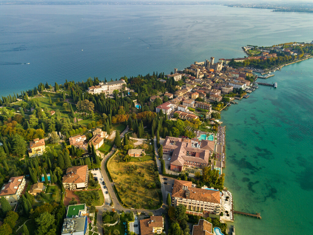 ripresa aerea della penisola di Sirmione sul Lago di Garda con case, vegetazione e acqua turchese ripresa aerea della penisola di Sirmione sul Lago di Garda con case, vegetazione e acqua turchese