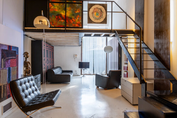 soggiorno di loft moderno e luminoso con soppalco, scala in metallo e divani di design